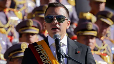 Getty Images Daniel Noboa delivers a speech during a military ceremony, while wearing a suit and sash