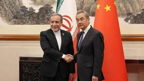 Anadolu via Getty Images Abbas Araqchi and Wang Yi shaking hands as they pose for a photo