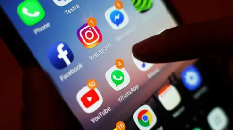 PA A finger touching a phone screen showing the apps of Facebook, Instagram, Messenger and Whatsapp 