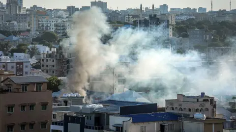 AFP via Getty Images Smoke rises over buildings in a residential area in Mogadishu