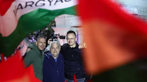 NurPhoto via Getty Images Three men link arms behind red and green flags