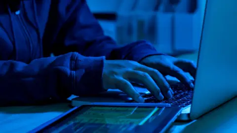 Getty Images A mock-up of a cyber criminal typing into a laptop