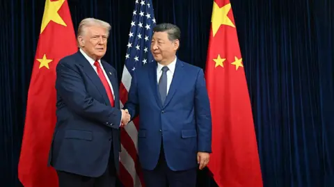 Getty Images US President Donald Trump (L) and China's President Xi Jinping shake hands as they arrive for talks at the Gimhae Air Base, located next to the Gimhae International Airport in Busan on October 30, 2025.