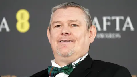 Getty Images John Davidson in a bow tie on the Baftas red carpet
