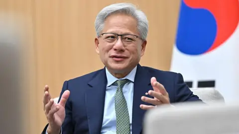 Getty Images A man in a dark navy blue suit is sat in front of a South Korean flag