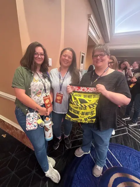 Friends hold up their crime-tape and blood-spatter adorned bag
