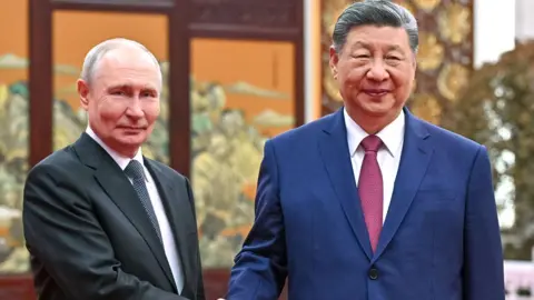 EPA Putin in a dark suit, white shirt and polkadot tie shakes the hands of Xo in a navy suit, red tie and white shirt. The two leaders meet a tea ceremony. 
