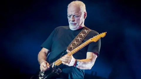 Neil Lupin/Redferns via Getty Images Gilmour during a concert where he is playing a black guitar