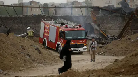 Anadolu via Getty Images A fire engine and firefighter are seen at the damaged Dil Aram-e Sina Psychiatric Hospital following the US and Israeli attack in Tehran, Iran on April 04, 2026