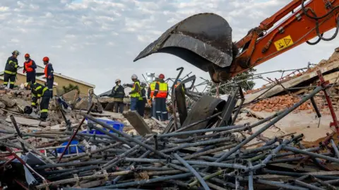 Getty Images Rescue workers continue their search and rescue efforts at the Neo Victoria apartment building in Victoria Street on May 07, 2024 in George, South Africa