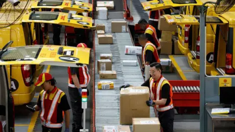 Bloomberg via Getty Images Employees sort packages inside the DHL Express Service Center facility in Shah Alam, Selangor, Malaysia.