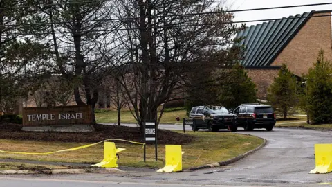 Getty Images view of the Temple Israel sign out front of the synagogue, with police cars and yellow tape in view