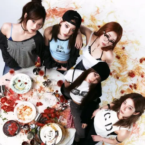Source Music Le Sserafim stand in the aftermath of a pasta-based food fight in a promotional image for their single, Spaghetti