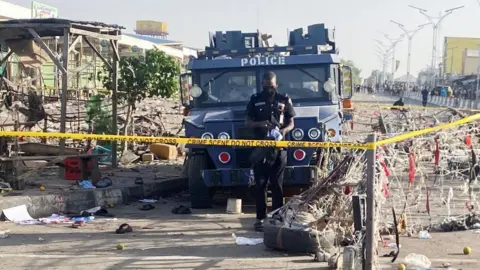Reuters A police truck and police officer are pictured amid the debris after a bombing at a market.