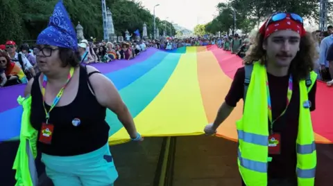 Reuters Two people hold a colourful flag