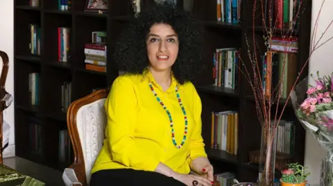 Getty Images Narges Mohammadi, a jailed Iranian women's rights advocate, sitting down in front of a bookcase