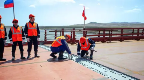 Russian Transport Ministry An image released by the Russian Transport Ministry showing construction workers connecting the two sides of the new road bridge