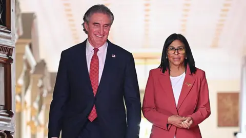 Getty Images Venezuela's interim president, Delcy Rodriguez and US Interior Secretary Doug Burgum walk side by side