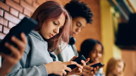 Getty Images A group of teenagers looking at their mobile phones.
