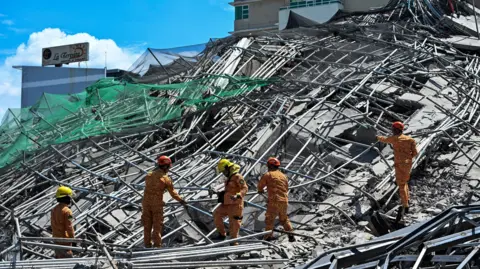 Reuters Rescue workers search through a pile of collapsed scaffolding and concrete.