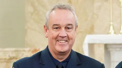 Victoria Police A middle-aged man with grey hair, smiling at the camera and wearing a dark blue suit