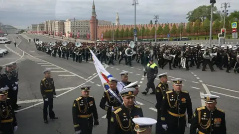 Getty Russian military servicemen walk in groups on an empty street with some holding brass instruments.
