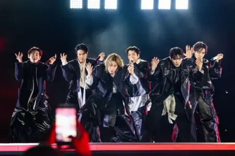 BIGHIT MUSIC AND NETFLIX The seven members of the band on stage, mid-dance