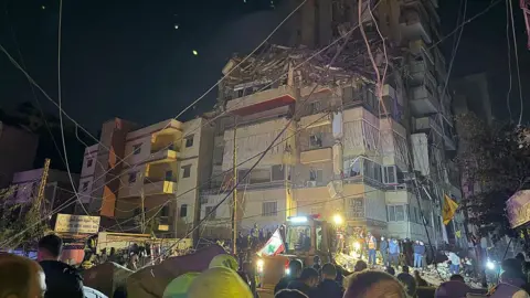 Getty Images Emergency service workers outside a damaged building in Beirut