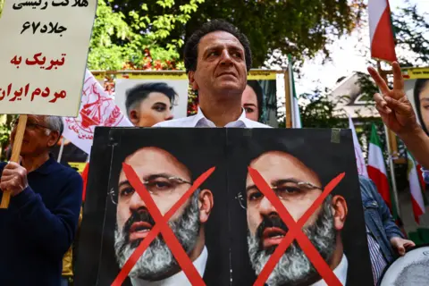 EPA Protesters in Berlin following the death of the death of President Raisi. A man stands with a poster, showing two faces of Raisi with red crosses through them