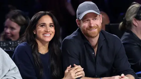 Getty Images Meghan, Duchess of Sussex and Prince Harry, Duke of Sussex sit courtside at a basketball game in California