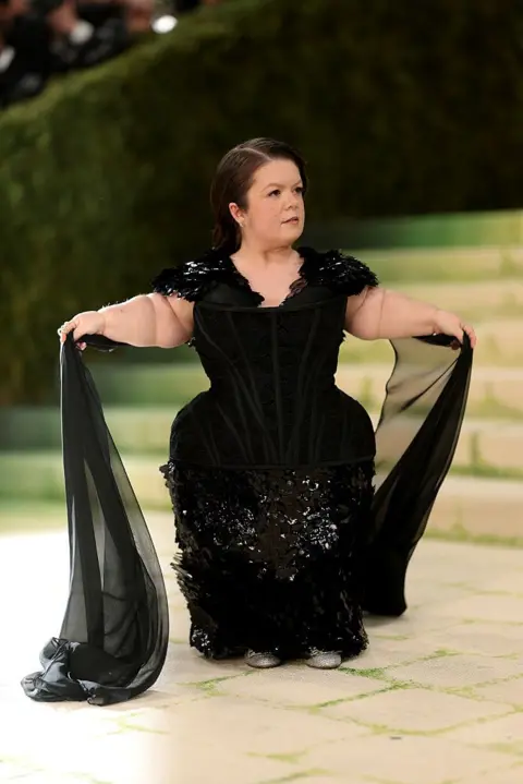 Getty Images Activist, writer, public speaker Sinéad Burke made her return to the Met Gala in a black corseted gown with flowing sleeve embellishments.
