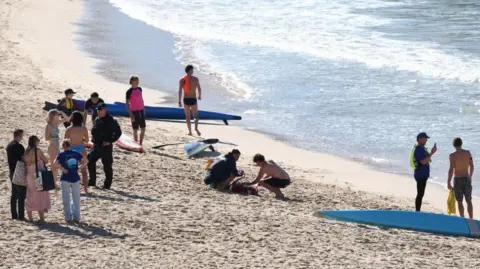 Reuters Police officers speak to people following a shark attack at Coogee Beach in Sydney, Australia. Photo: 13 June 2026