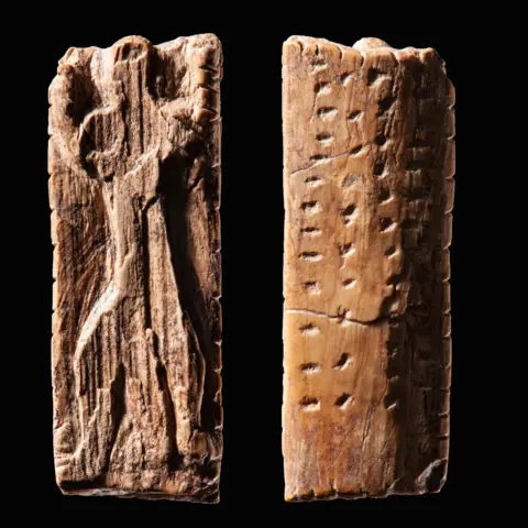 Landesmuseum Württemberg / Hendrik Zwietasch Small ivory plaque with an anthropomorphic figure and several rows of notches and dots. Front and back view of the same plaque.