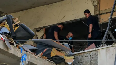 Reuters People inspect the damage inside a building following an Israeli strike on the southern suburbs of Beirut.