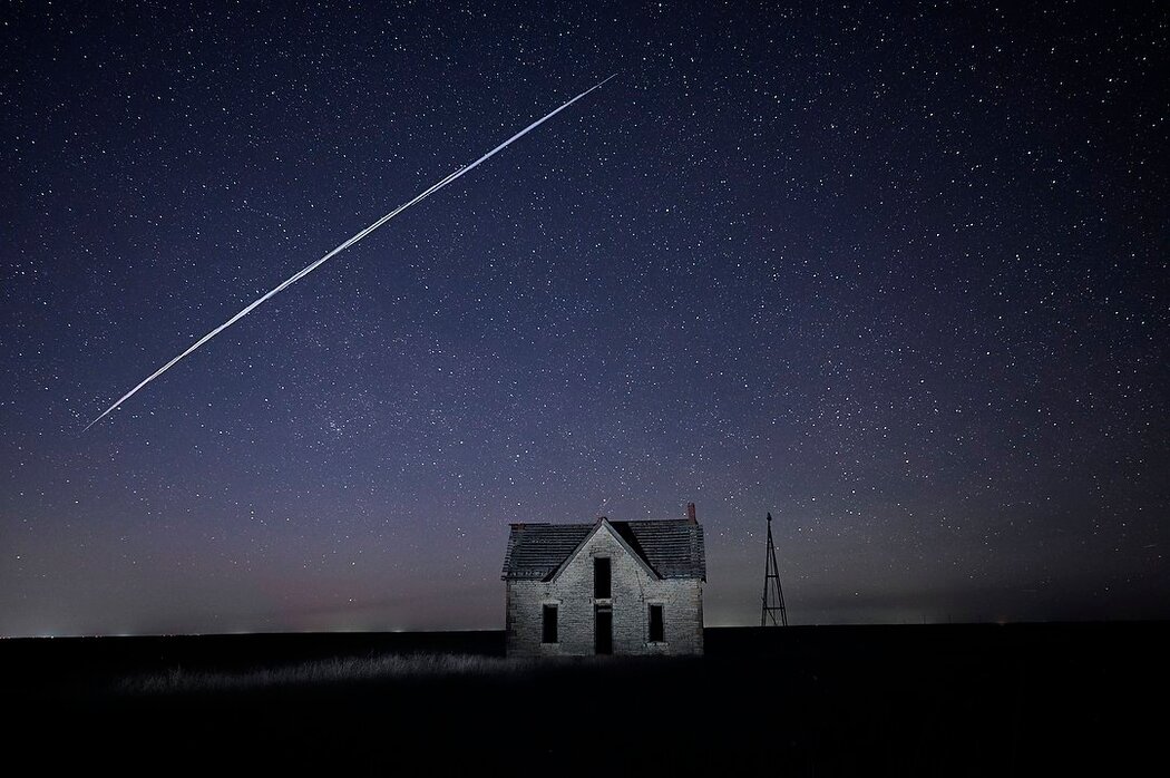 這張2021年拍攝的長時間曝光照片記錄了SpaceX的一個星鏈衛星穿過堪薩斯州佛羅倫斯附近一棟古老石屋上空的景致。