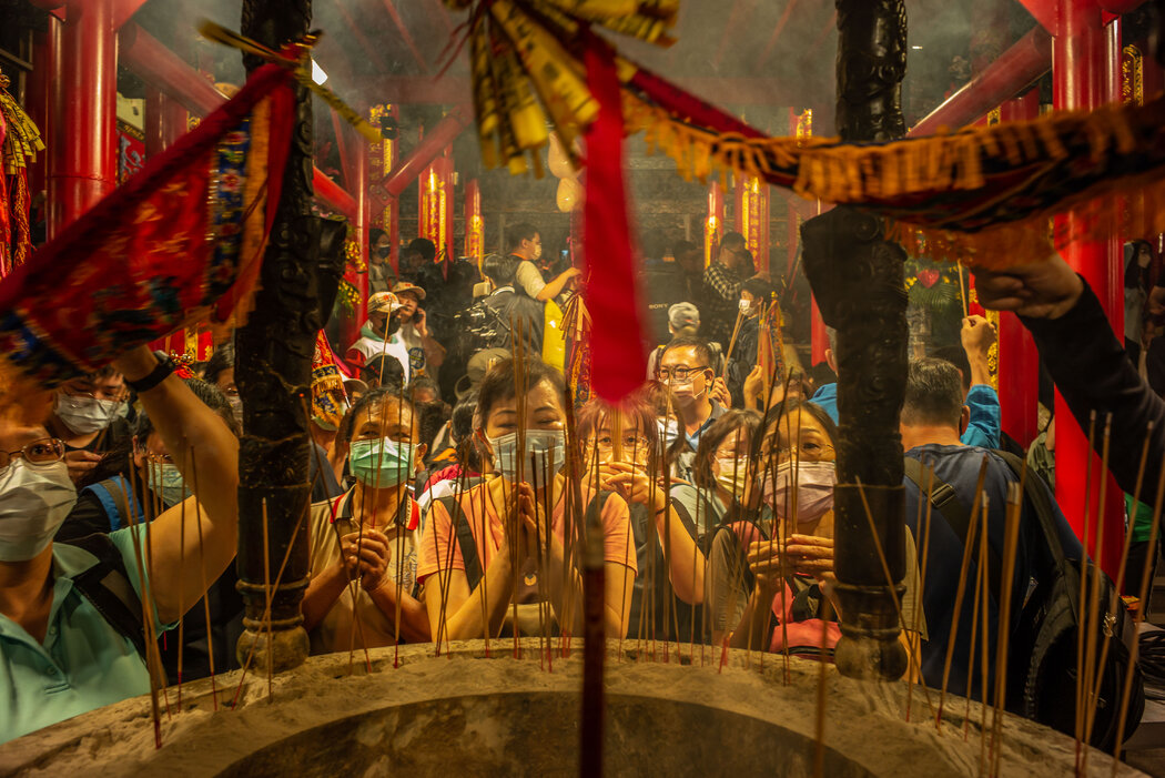 媽祖的追隨者在一座寺廟的媽祖像前鞠躬並點燃香火。