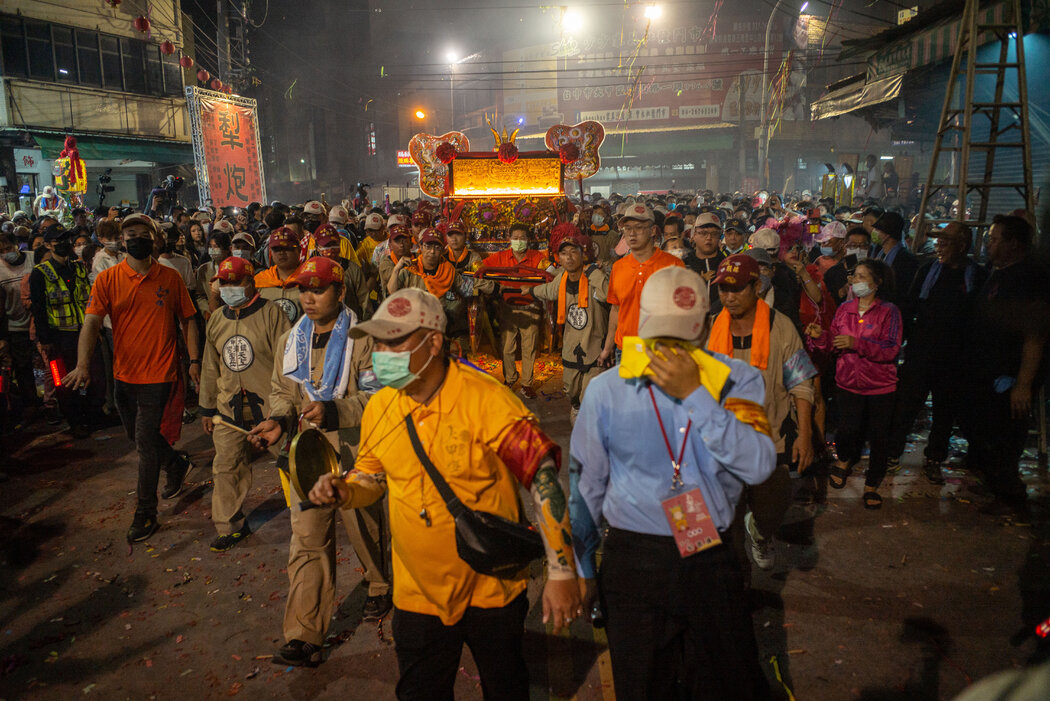 抬著媽祖穿過人群。近年來,許多台灣年輕人參加了進香活動。