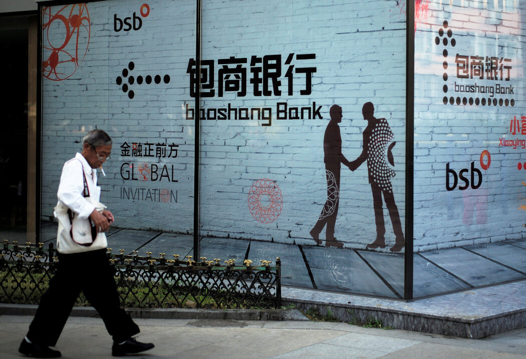 一名男子走過包商銀行的街頭廣告, 肖建華控制的該銀行於2020年申請破產。