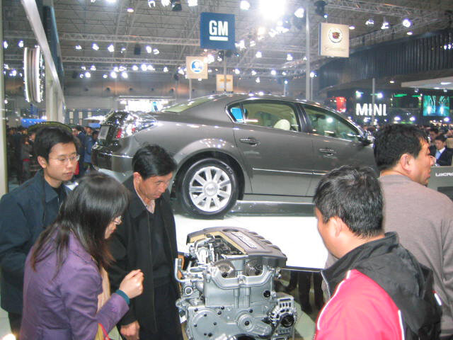 2006年北京車展開幕日,在通用汽車展台,參觀者正在觀看一台擺放在別克君越轎車旁的發動機。