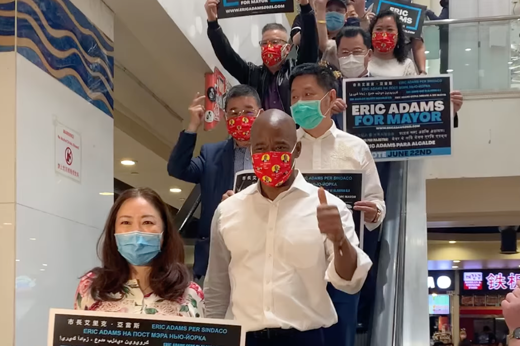 2021年市長競選期間，亞當斯出席在邵連武的皇后區法拉盛新世界商城舉行的集會。戴著綠色口罩的邵連武站在亞當斯身後。