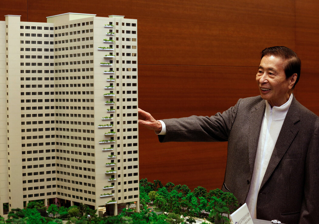 2015年，李兆基與計劃建造的公寓樓模型合影。他就住在他的公司建造的一棟大樓之一。