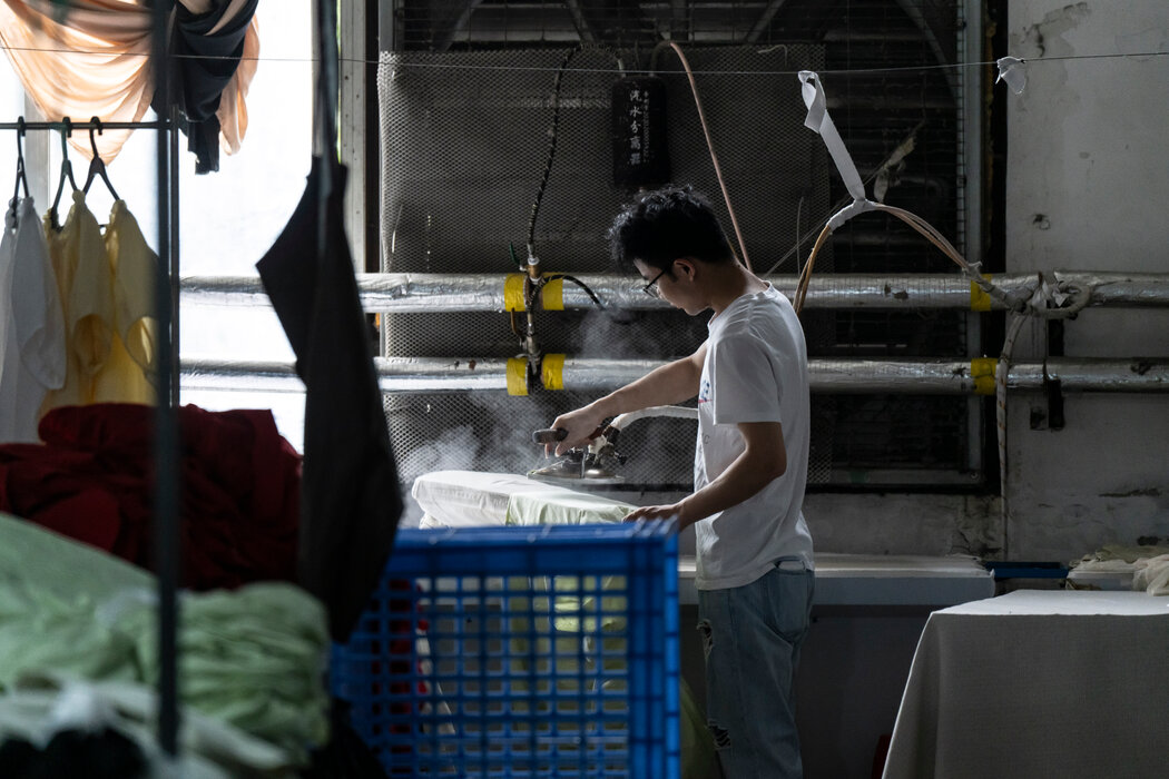 週三，中國廣州一家服裝廠的工人在熨燙麵料。