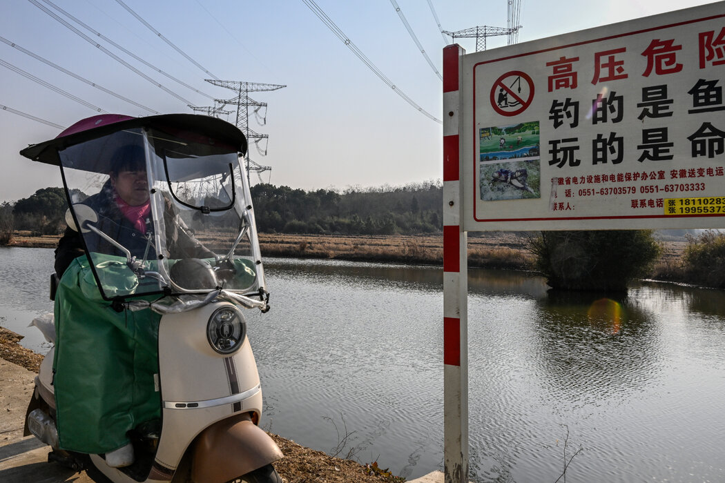 一塊警示村民禁止在魚塘釣魚的牌子,上面有一名觸電燒傷者的照片。