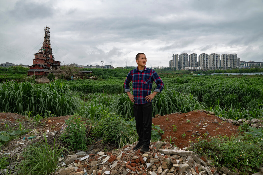 陳天明在他家附近,身後是新建的公寓樓。