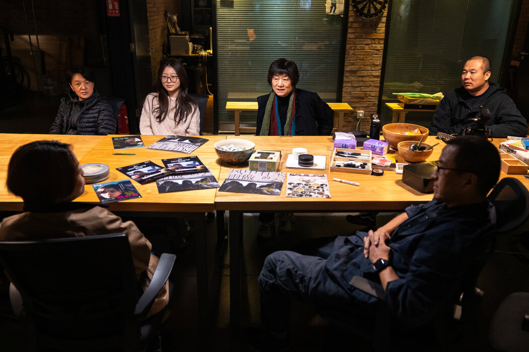 婁燁的妻子及經常合作的編劇馬英力(戴著彩色圍巾)正在工作室裡與婁燁及其他團隊成員交談。