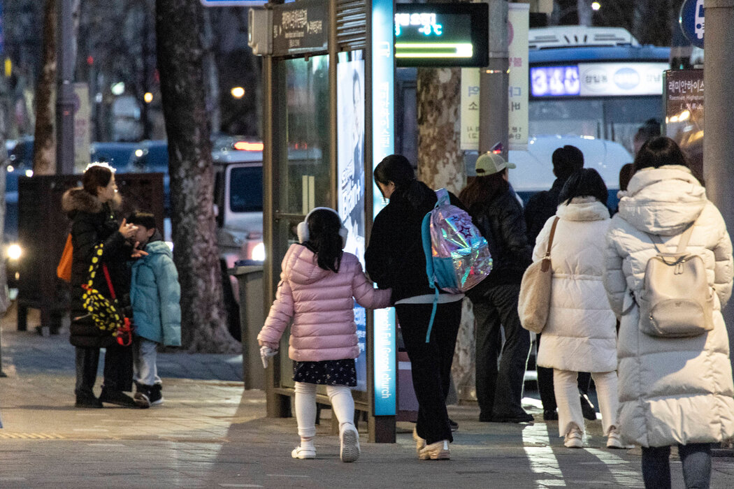 首爾常見景象：母親們從夜間補習班接孩子，背著孩子的書包。
