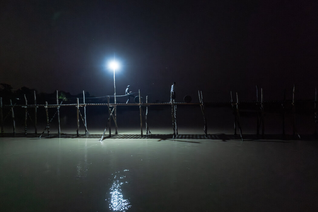夜間推著油桶穿過一座小橋,向偏遠村莊供應物資。