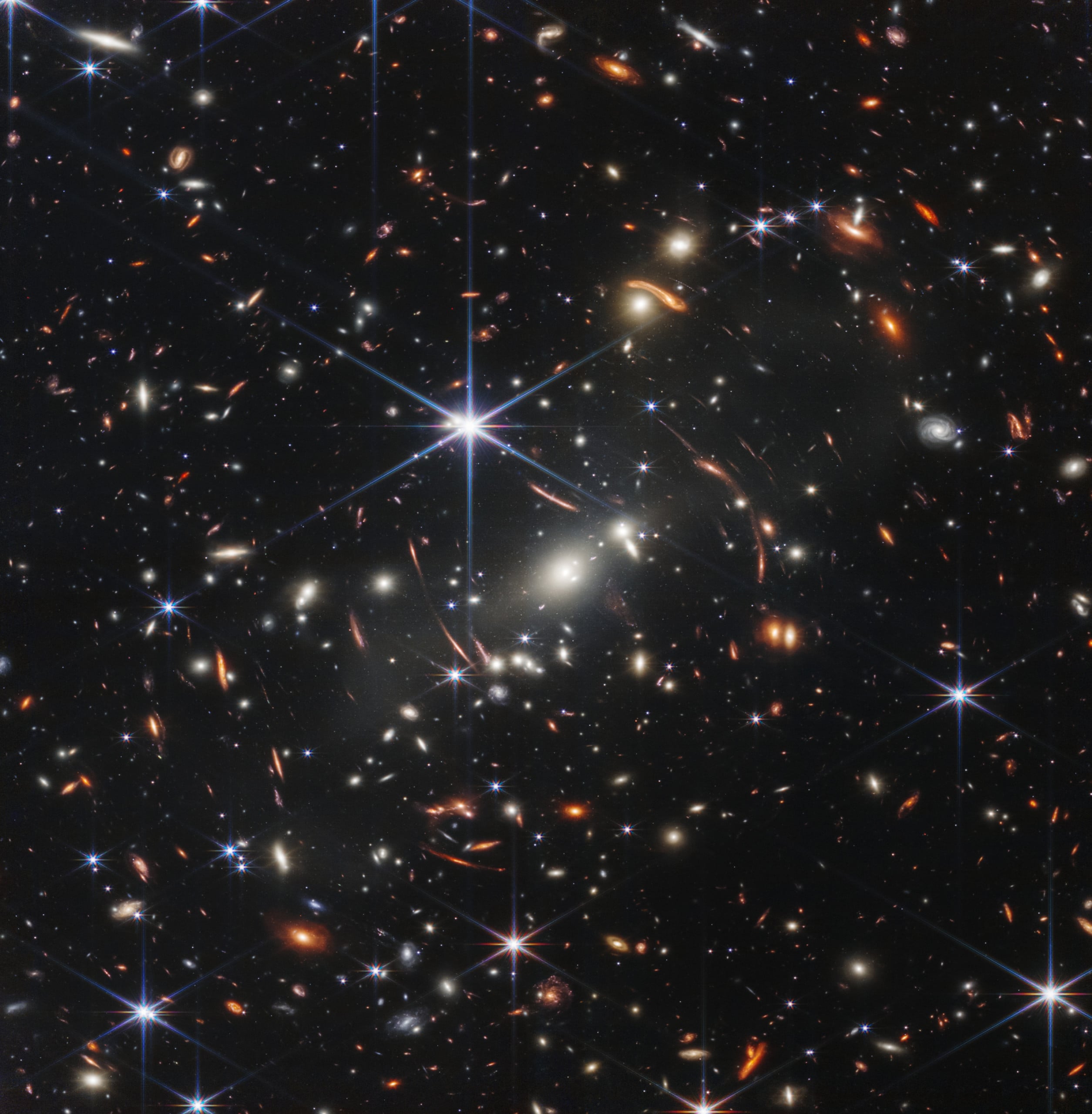 deep space photo showing hundreds of small individual galaxies and stars with spiral structures