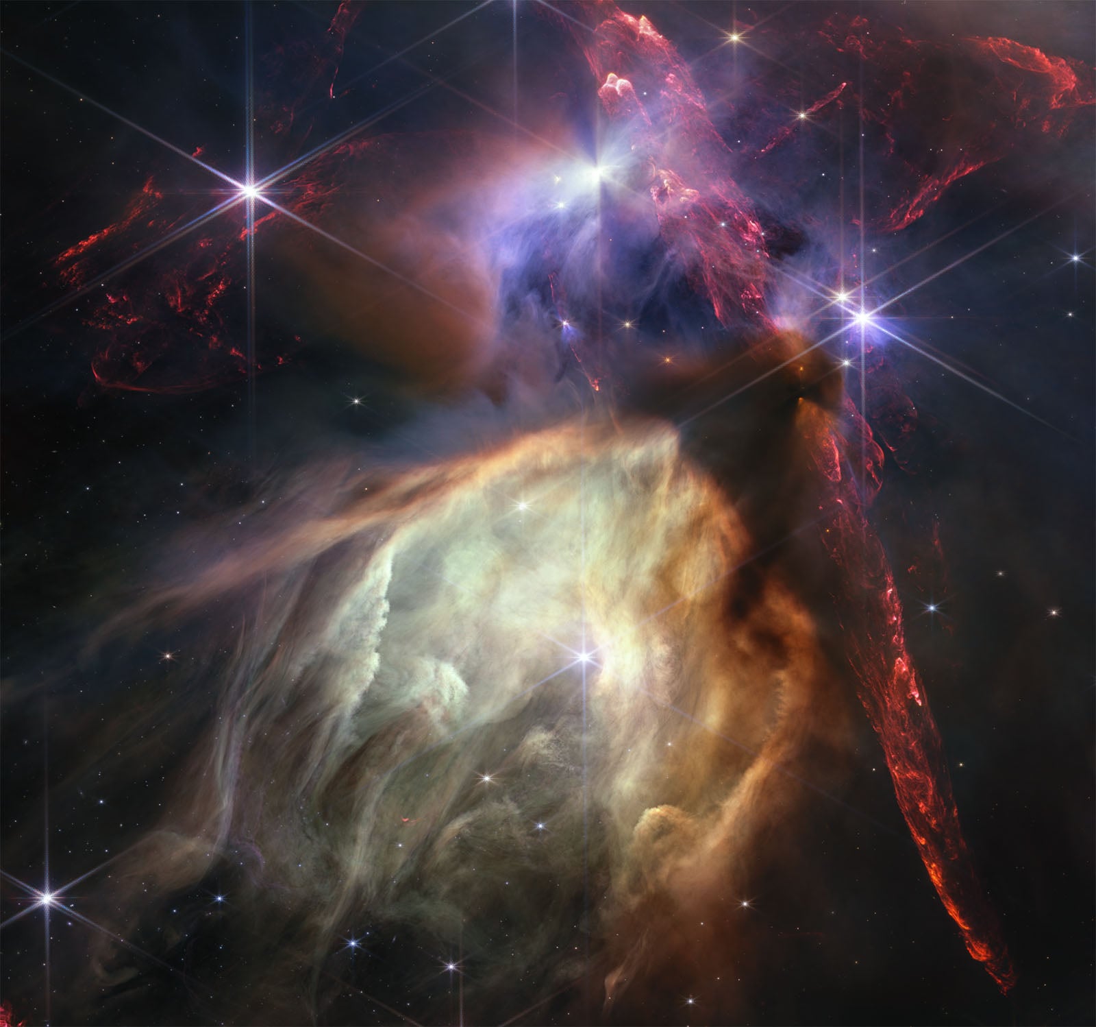A vibrant space image depicting a nebula with swirling clouds of gas in orange and blue hues, illuminated by bright stars scattered across the frame.