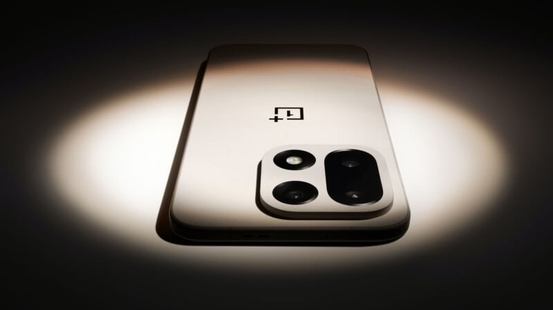 A metallic smartphone with a large dual-lens rear camera module, showcased under a spotlight, featuring the OnePlus logo on the back.